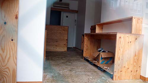 玄関扉のガラス越しに見た什器が設置されたカーサ・オレアリア・パーチェの現場の状況