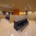 店舗デザイン設計実績事例-三宮一貫樓-元町本店2階-店内全景-豚まんをアイコン化したドットグラフィックに覆われた壁とアクセントのオレンジの壁