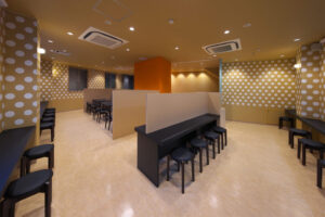 店舗デザイン設計実績事例-三宮一貫樓-元町本店2階-店内全景-豚まんをアイコン化したドットグラフィックに覆われた壁とアクセントのオレンジの壁