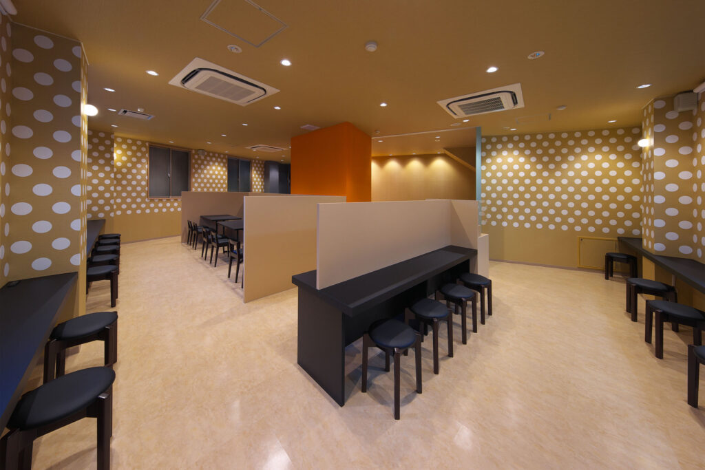 店舗デザイン設計実績事例-三宮一貫樓-元町本店2階-店内全景-豚まんをアイコン化したドットグラフィックに覆われた壁とアクセントのオレンジの壁