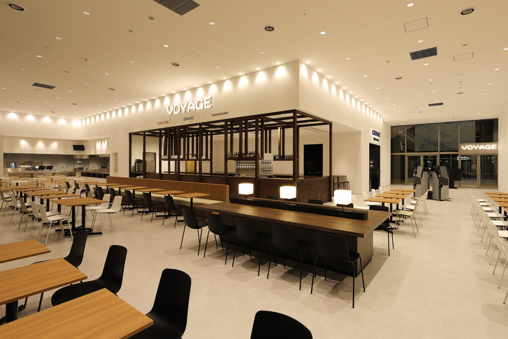 店舗デザイン設計実績事例-飲食店ビアレストラン学食-VOYAGE(ボヤージュ)神奈川大学みなとみらいキャンパス-横浜-高さのある垂壁への連続したダウンライト照明が空間にリズムを与え美しい