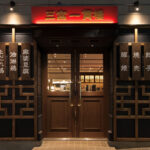 店舗デザイン設計実績事例、神戸の中華料理店三宮一貫樓元町北店店舗外観、暖かい雰囲気の店内が見える入口扉