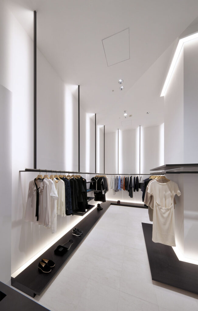 物販店舗デザイン設計実績事例、大阪梅田アパレルセレクトショップ、ピュアポニーディアモール大阪店、壁面のハンガーパイプを支える支柱。部材を出来るだけ細くし、間接照明を入れ、天井の高さを強調している。