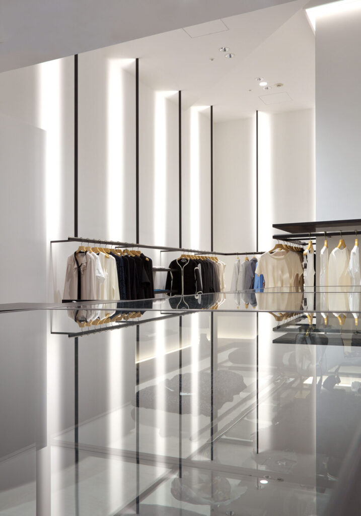 物販店舗デザイン設計実績事例、大阪梅田アパレルセレクトショップ、ピュアポニーディアモール大阪店、棚のガラスに映り込む間接照明を仕込んだ支柱の連続
