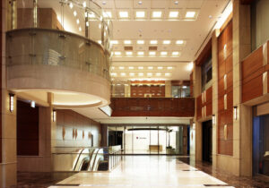 商業施設商環境デザイン実績事例、淀屋橋オドナ、A棟1階ロビー。不燃無垢木材で仕上げられた上質で温かみのある壁と大理石の角錐は水面の波をイメージ。