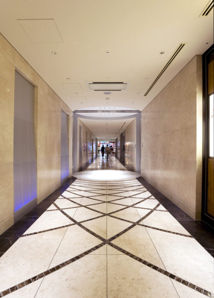 商業施設商環境デザイン実績事例、淀屋橋オドナ、A棟2階。設備スペースに面した長い通路を、円形のポイントとカラーライティングで歩きたくなる場所に。